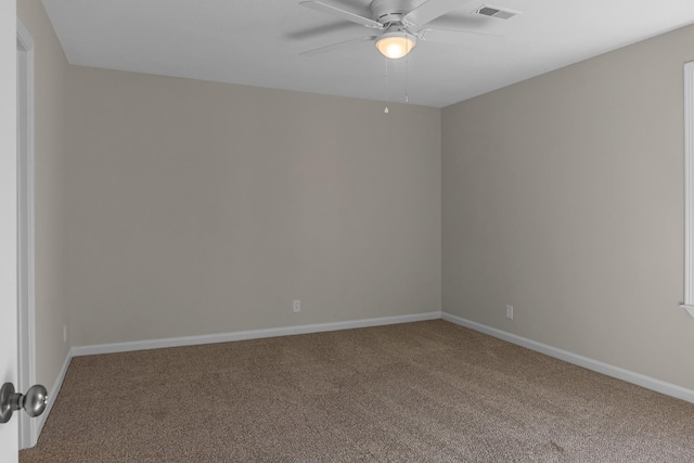 empty room with carpet floors, baseboards, visible vents, and a ceiling fan