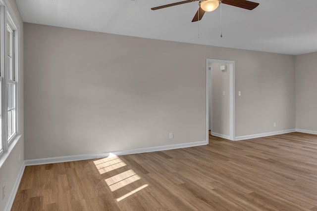 spare room featuring ceiling fan, baseboards, and wood finished floors