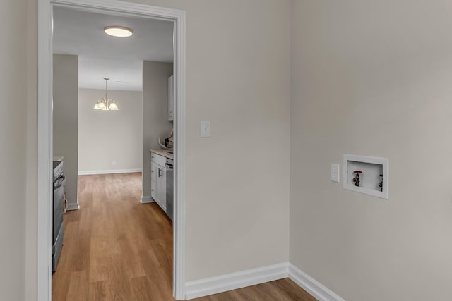 kitchen featuring light wood-style floors, light countertops, a notable chandelier, and baseboards