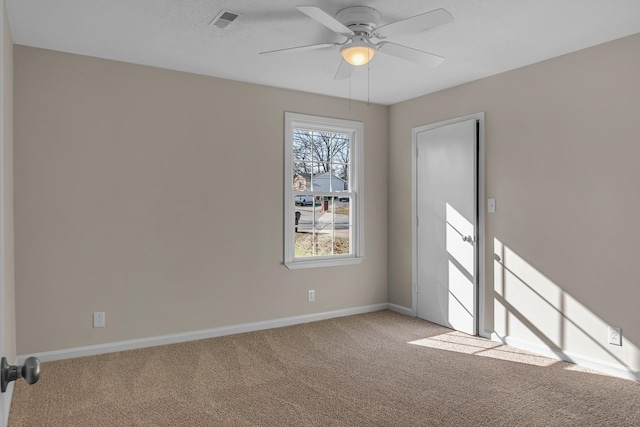 empty room featuring carpet, visible vents, ceiling fan, and baseboards