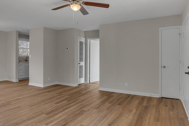 unfurnished room featuring ceiling fan, light wood finished floors, and baseboards