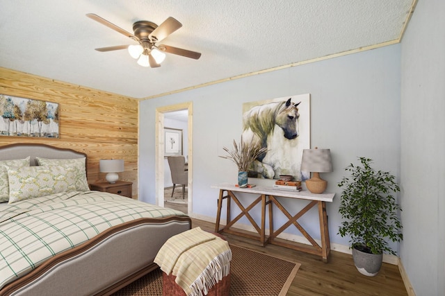 bedroom with baseboards, ceiling fan, wood finished floors, a textured ceiling, and wood walls