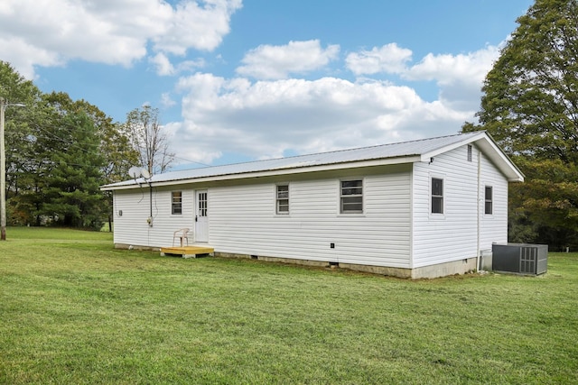 back of property with crawl space, central AC unit, metal roof, and a lawn