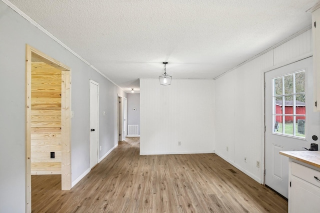 unfurnished room with ornamental molding, visible vents, a textured ceiling, and light wood finished floors