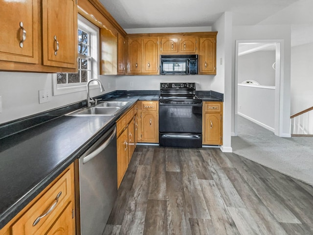 kitchen featuring dark wood-type flooring, a sink, brown cabinets, black appliances, and dark countertops