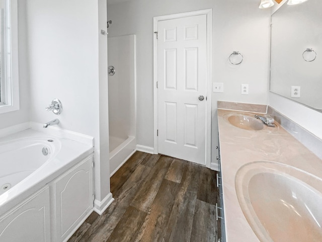 bathroom with double vanity, a sink, wood finished floors, a jetted tub, and walk in shower