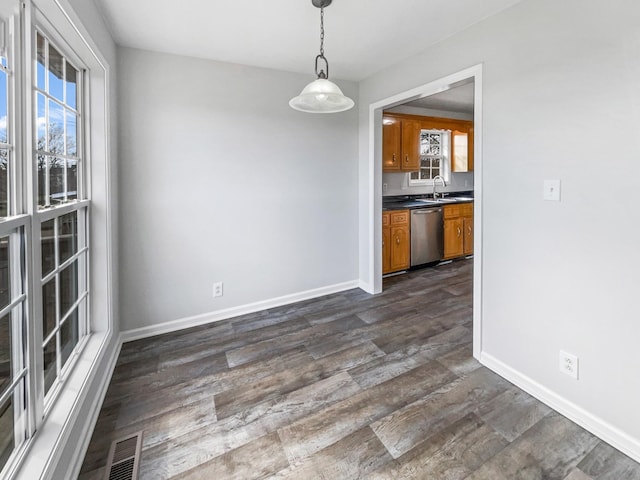 unfurnished dining area with a healthy amount of sunlight, baseboards, visible vents, and dark wood-type flooring