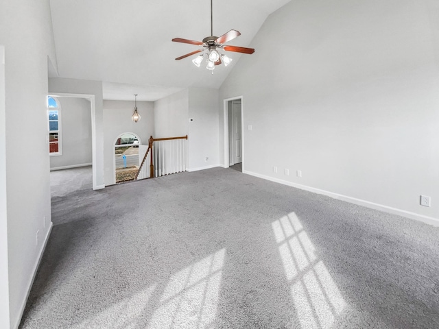 carpeted empty room with ceiling fan, high vaulted ceiling, and baseboards