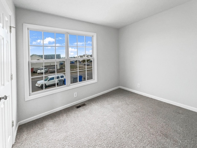 spare room with carpet floors, baseboards, and visible vents