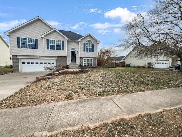 raised ranch with an attached garage, fence, and concrete driveway