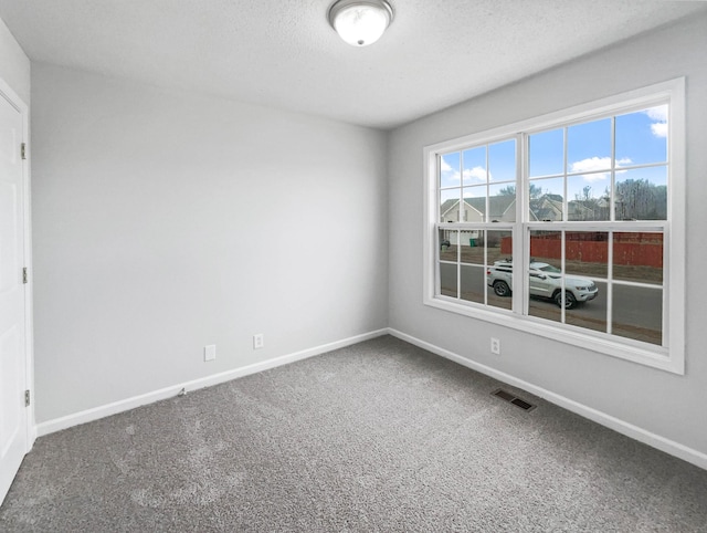 unfurnished room with baseboards, visible vents, a textured ceiling, and carpet flooring