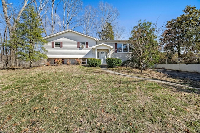 split foyer home featuring a front lawn and fence