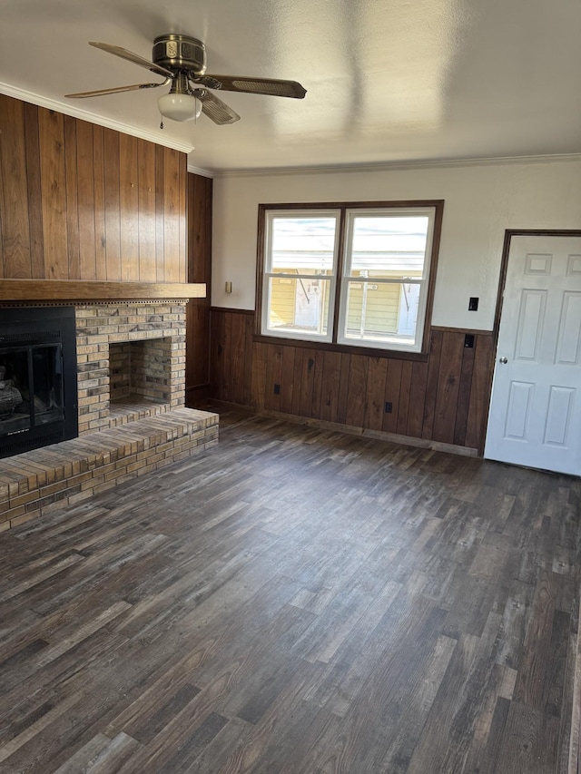 unfurnished living room with a brick fireplace, wainscoting, and crown molding