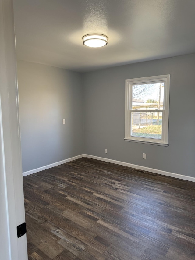 spare room featuring baseboards and dark wood-style flooring