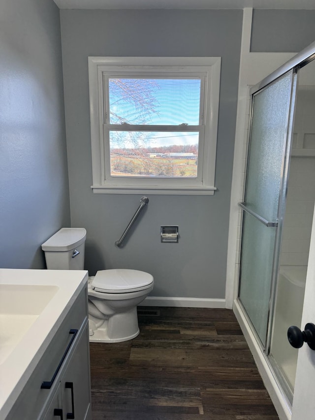 full bath with toilet, a shower with door, baseboards, and wood finished floors