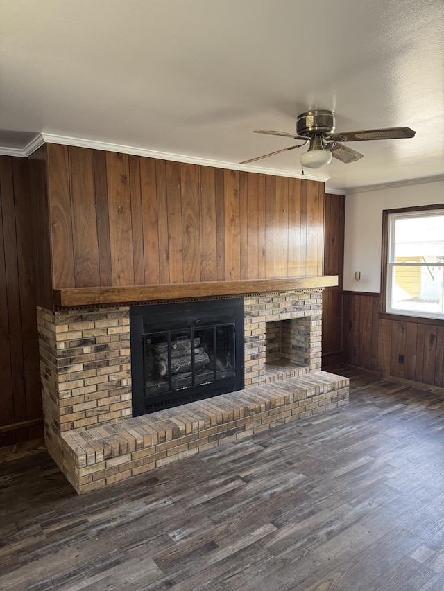 unfurnished living room with a wainscoted wall, ornamental molding, a fireplace, and wood finished floors