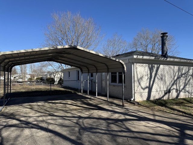 view of parking featuring aphalt driveway, a detached carport, and fence