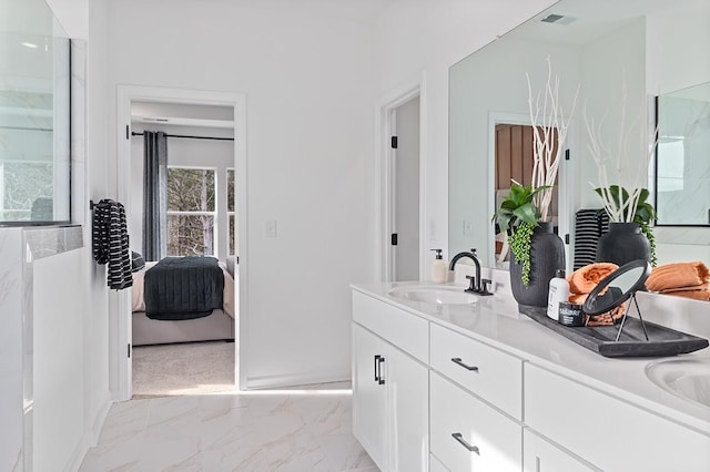 ensuite bathroom with a sink, connected bathroom, marble finish floor, and double vanity