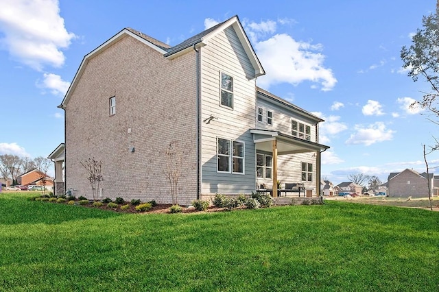 rear view of house featuring brick siding and a yard