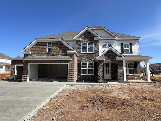 view of front of house with stone siding, driveway, a garage, and roof with shingles