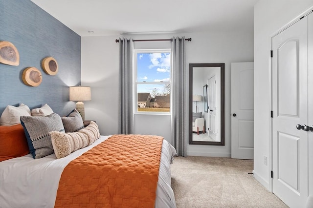 bedroom featuring light colored carpet, wallpapered walls, an accent wall, and baseboards