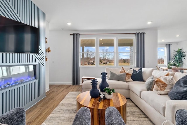 living area featuring recessed lighting, a fireplace, light wood-type flooring, and baseboards