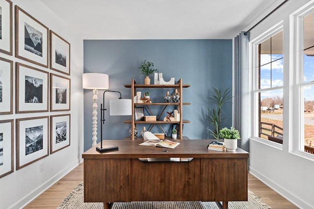 home office with light wood-type flooring, baseboards, and a healthy amount of sunlight