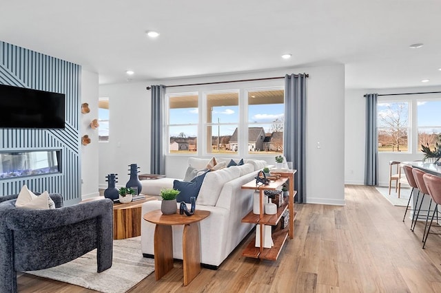 living room with a fireplace, recessed lighting, baseboards, and light wood finished floors