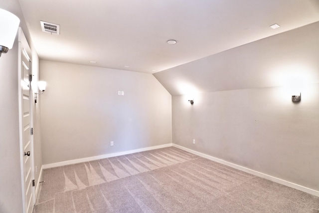 interior space with carpet, visible vents, baseboards, and vaulted ceiling