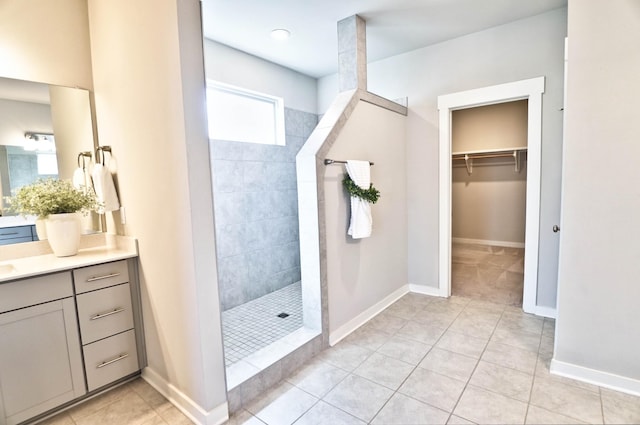 full bath featuring baseboards, walk in shower, vanity, and tile patterned floors