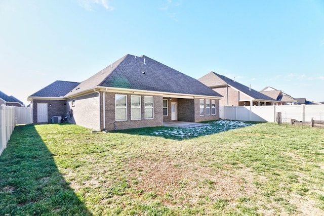 rear view of house with a yard, brick siding, and a fenced backyard