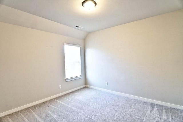 unfurnished room featuring light colored carpet, visible vents, vaulted ceiling, and baseboards