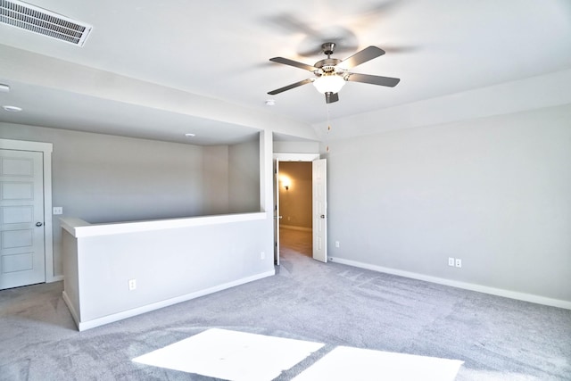 carpeted spare room featuring baseboards, visible vents, and a ceiling fan