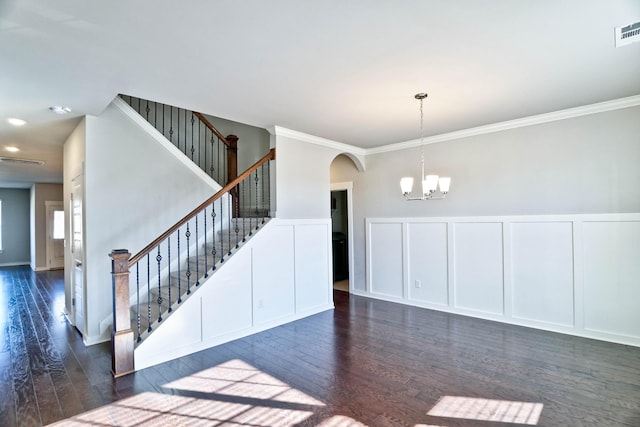 empty room featuring dark wood-style floors, arched walkways, a decorative wall, a chandelier, and stairs