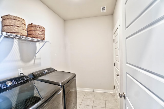 laundry room with light tile patterned floors, visible vents, washing machine and dryer, laundry area, and baseboards