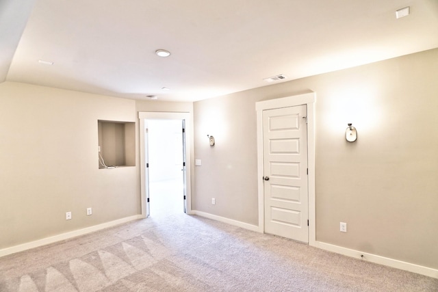 carpeted spare room with visible vents and baseboards