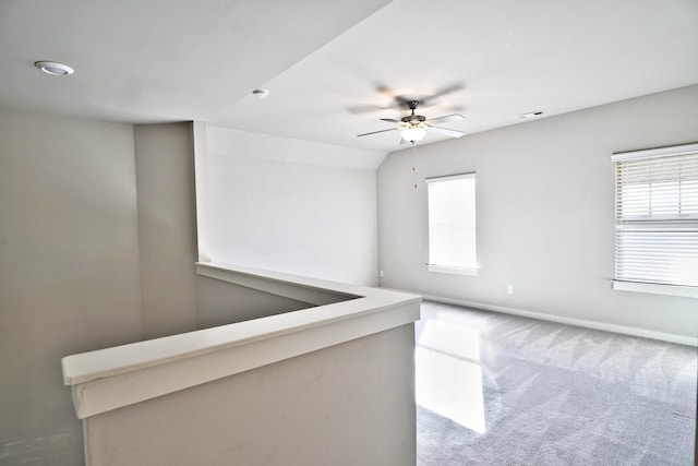 carpeted empty room with vaulted ceiling, visible vents, a ceiling fan, and baseboards