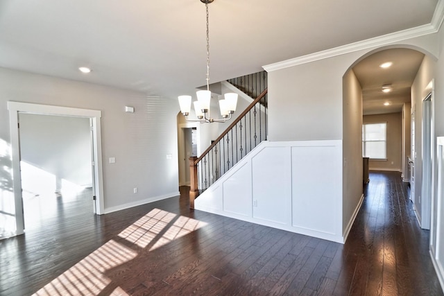 interior space with arched walkways, dark wood-style flooring, a notable chandelier, and stairway