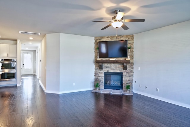 unfurnished living room featuring dark wood-style floors, a fireplace, visible vents, ceiling fan, and baseboards