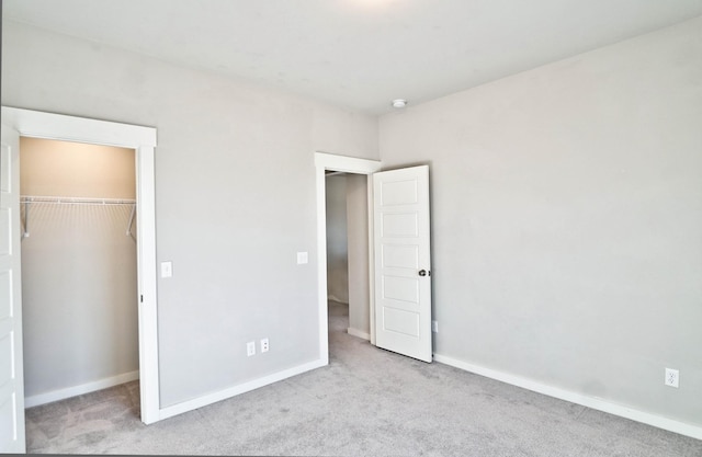 unfurnished bedroom featuring a spacious closet, a closet, carpet flooring, and baseboards