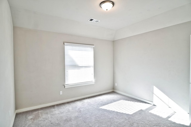 carpeted empty room featuring baseboards, visible vents, and vaulted ceiling