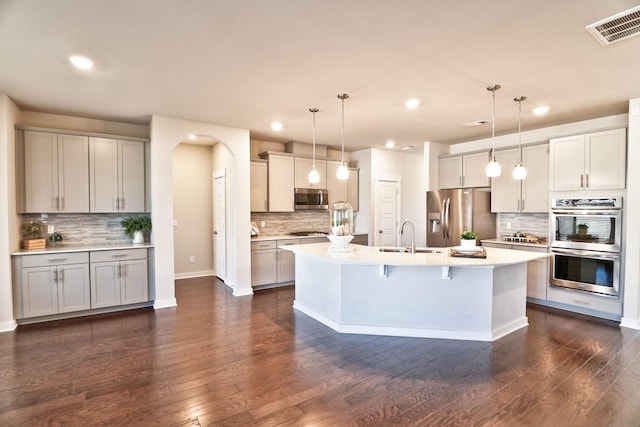 kitchen with arched walkways, a sink, visible vents, light countertops, and appliances with stainless steel finishes