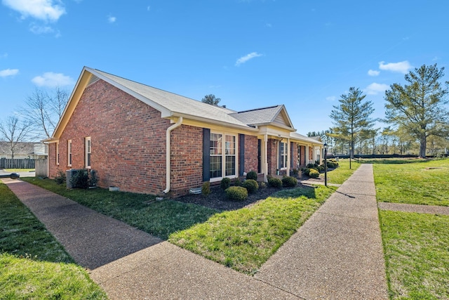 view of property exterior with a yard, cooling unit, and brick siding