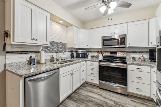 kitchen with tasteful backsplash, stainless steel appliances, light wood-style floors, white cabinetry, and a sink