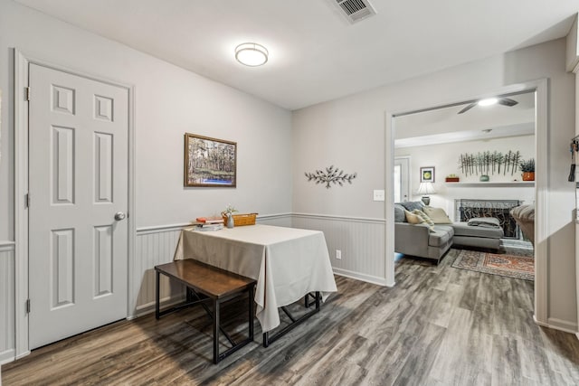 dining area with wainscoting, visible vents, a fireplace, and wood finished floors