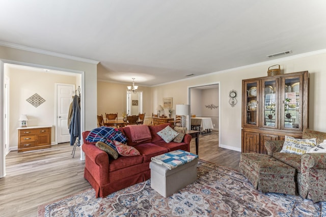 living area featuring a chandelier, ornamental molding, visible vents, and light wood-style floors