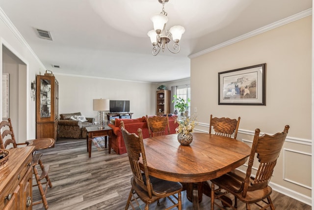 dining area with a chandelier, a wainscoted wall, visible vents, ornamental molding, and dark wood-style floors