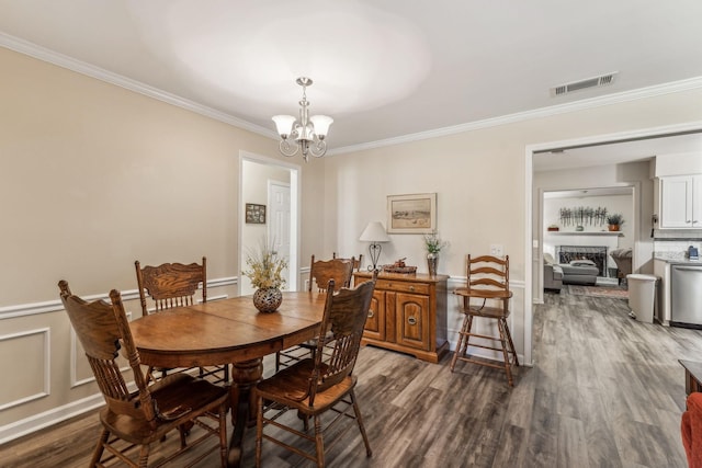 dining area with a fireplace, visible vents, dark wood-style floors, an inviting chandelier, and crown molding