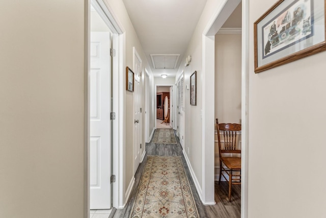 hallway with attic access, baseboards, and wood finished floors