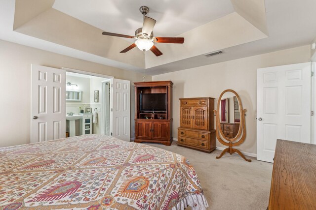 bedroom with a raised ceiling, light colored carpet, visible vents, a ceiling fan, and baseboards